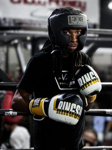 Focused boxer wearing headgear and gloves in a gym ring.