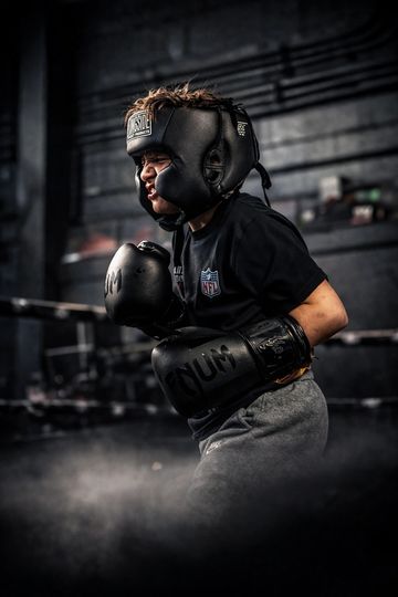 Young boxer intensely training with gloves and headgear in a gym.