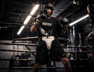 Young boxer in protective gear practicing in a dimly lit gym.
