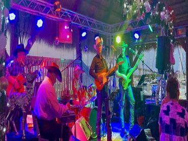 Country band performing live on a decorated stage with colorful lights.