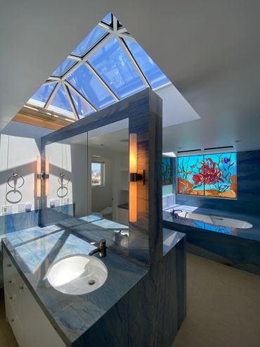 Bright bathroom with blue marble surfaces and colorful stained glass window.