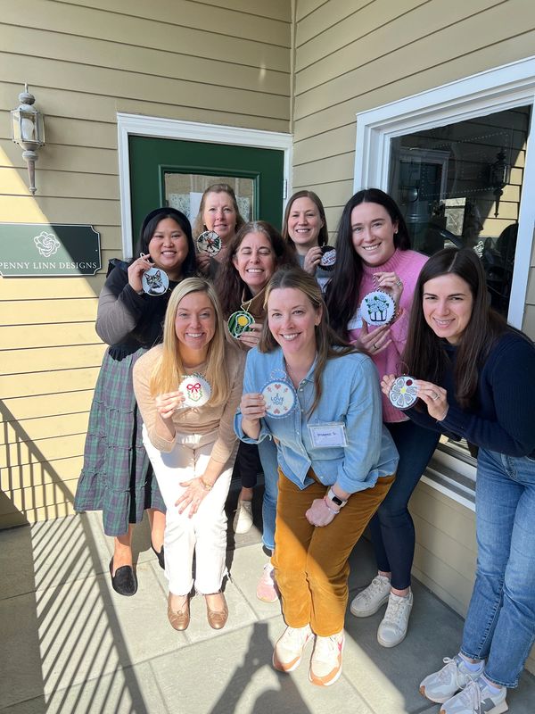 Group of people smiling with finished needlepoint ornaments