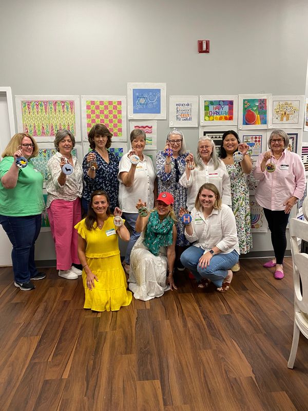 Group of people smiling with finished needlepoint ornaments