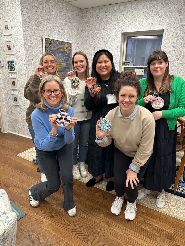 Group of people smiling with finished needlepoint ornaments