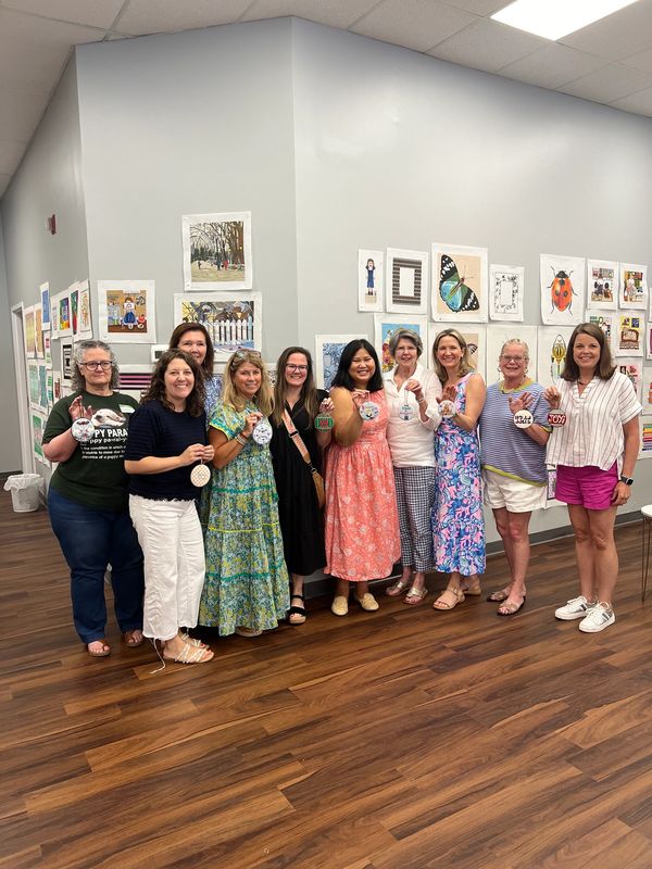 Group of people smiling with finished needlepoint ornaments