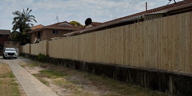 Residential area with wooden fence and cloudy sky.