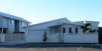 Modern single-story house with white exterior and fenced front yard.