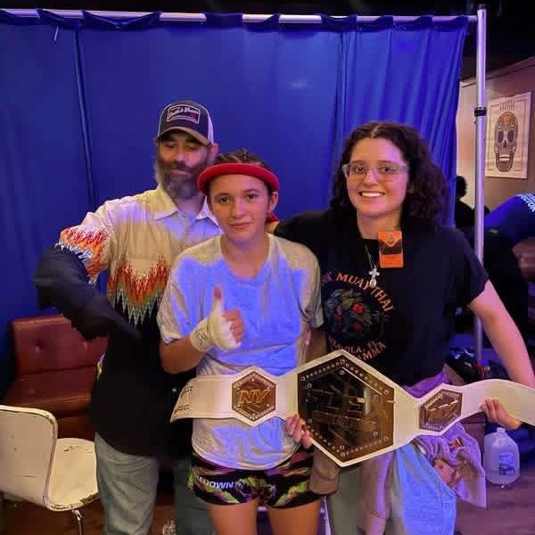 Teenage champion with two supporters holding a championship belt.