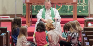 Pastor Chris sitting on the floor with a group of children