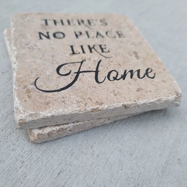 Stone coasters with the phrase "there's no place like home" hand painted on it