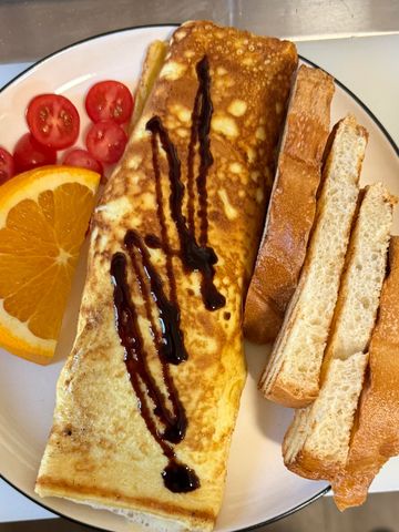 Plate with a rolled omelette, toast, orange slice, and cherry tomatoes.