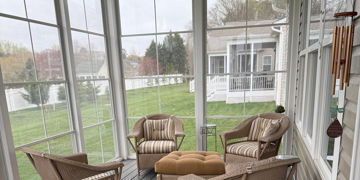 Cozy Eze-Breeze vinyl porch with wicker chairs and a view of a green lawn.