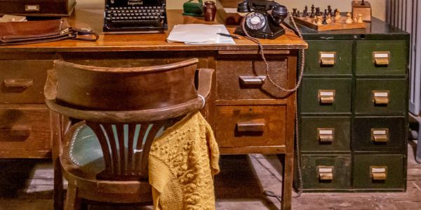 Vintage office desk with a wooden chair and old telephone.