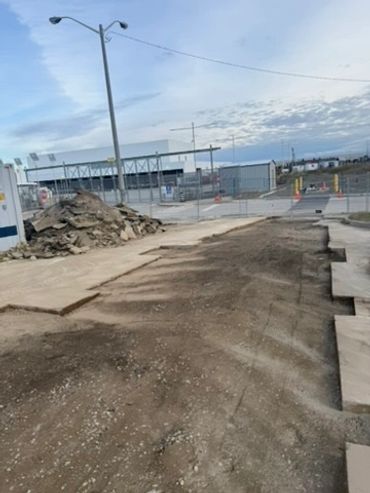 Construction site with excavated ground and concrete slabs.