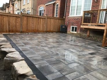 Newly paved backyard patio with stone tiles and wooden fence.