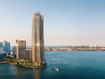Modern high-rise building near water body at sunset.