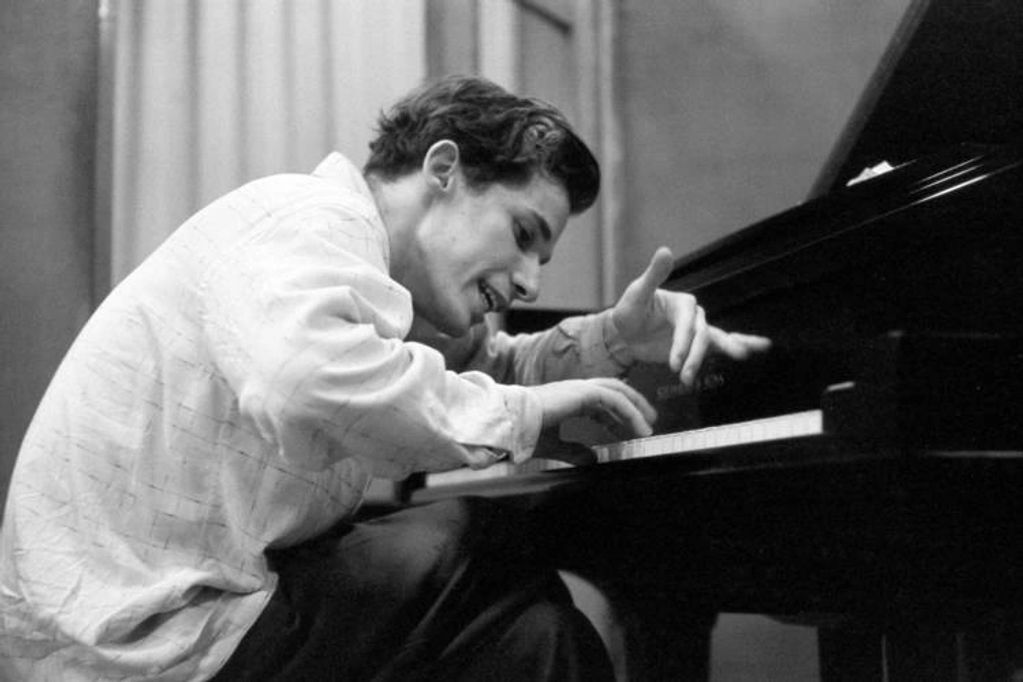Man passionately playing piano with expressive hand movements.