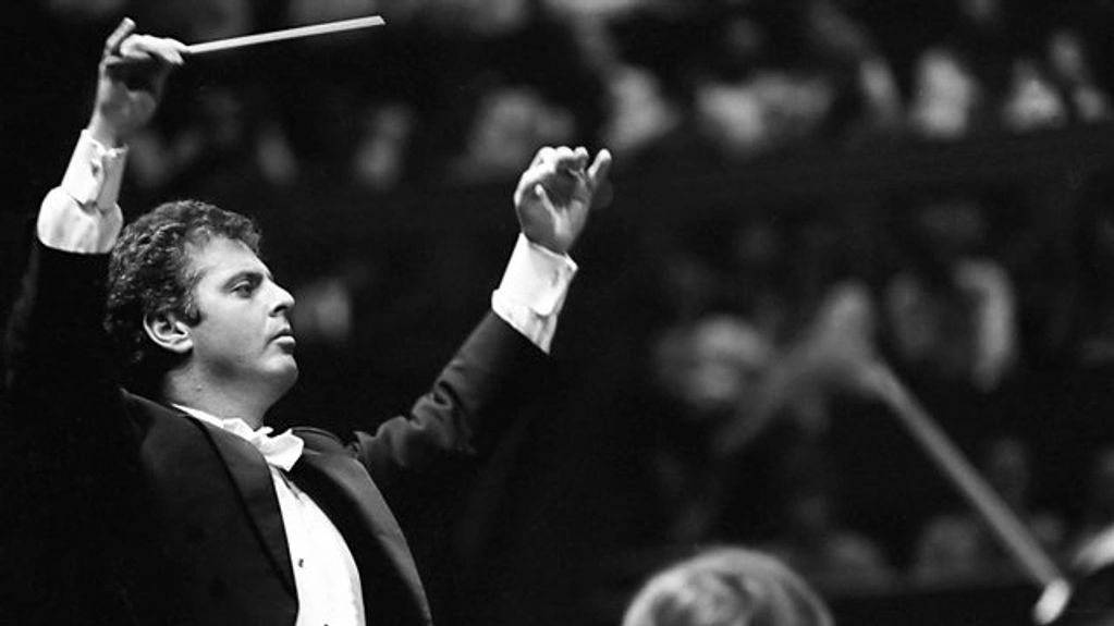 A conductor passionately leading an orchestra with raised arms and baton.