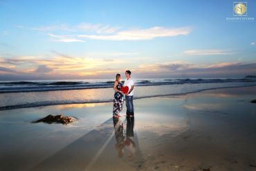 Romantic photo of a couple on the beach at sunset. The sky is a beautiful color, the couple is water