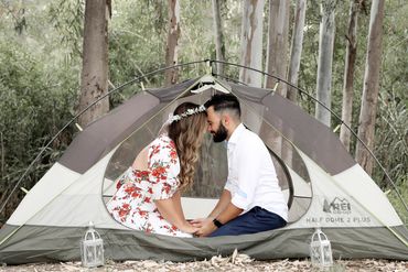 Engaged couple in the woods a tent kissing