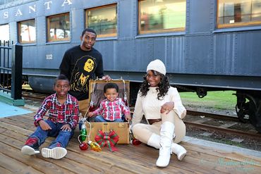Fun Family Photo of a Mom with her  3 boys in front of old train. The youngest boy is in a suitcase.