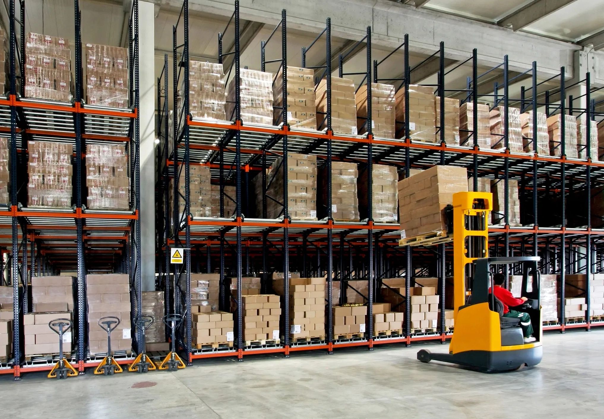 Warehouse with stacked boxes and a forklift in operation.