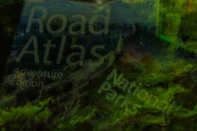 Road Atlas and National Parks Guide reflection in windshield on a rainy day in Olympic NP.