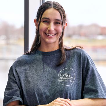 Jeune femme souriante en t-shirt gris de l'École de Danse de Boucherville.