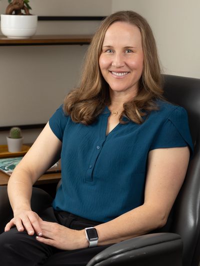 Woman sitting comfortably in an office chair, smiling warmly.