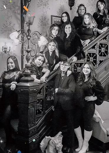 Group of eleven women posing on a vintage staircase in black and white.