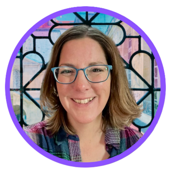 Elizabeth is smiling and wearing teal glasses. The background is stained glass.