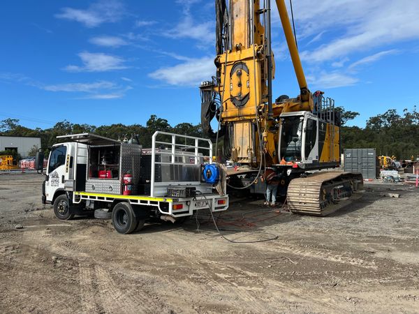 Construction vehicles and equipment on a dirt site under a blue sky.