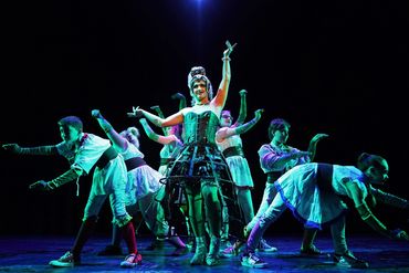 A theatrical dance performance with elaborate costumes and dramatic lighting.