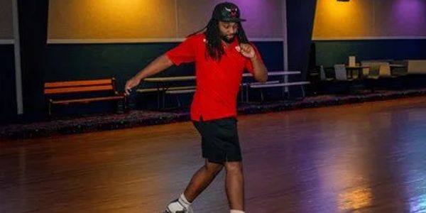 Person roller skating indoors wearing a red shirt.