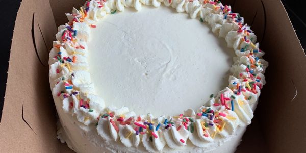Vanilla cake with white frosting and colorful sprinkles.