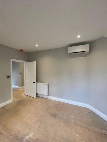 Empty room with gray walls, wooden floor, and white door.