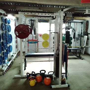 Home gym with colorful weight plates and kettlebells organized on walls and floor. We have everything you need to get fit and strong