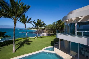 Luxury beachfront home with pool and palm trees.