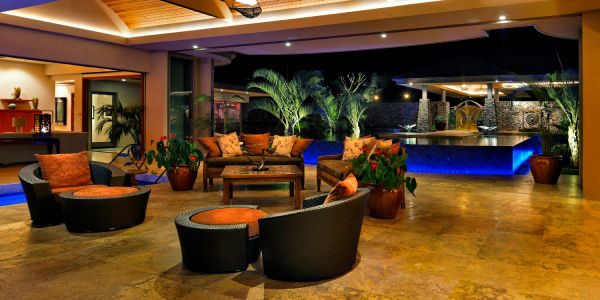 Luxurious outdoor lounge with modern furniture and blue-lit pool at night.