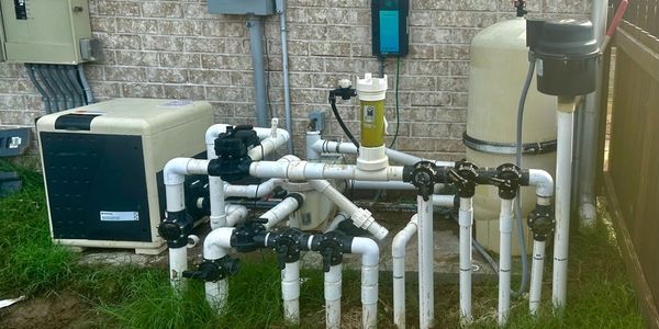Complex outdoor pool filtration and pump system with multiple pipes and valves.
