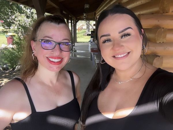 Two smiling women posing for a selfie outdoors on a sunny day.