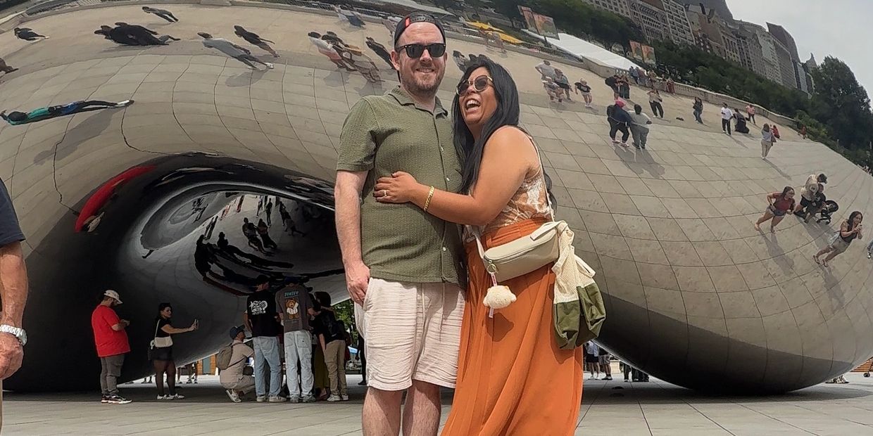 Couple smiling in front of The Bean in Chicago.