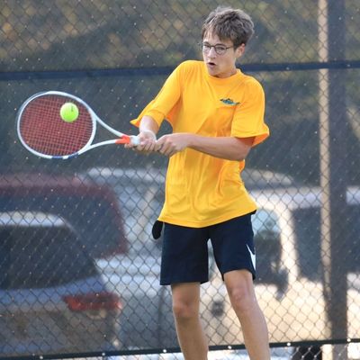 player in glasses hitting tennis ball with racquet