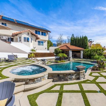 Backyard with pool and hot tub under a clear blue sky.