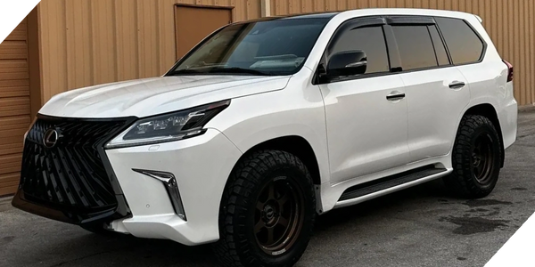 White Lexus SUV parked outside a beige building with tinted windows.