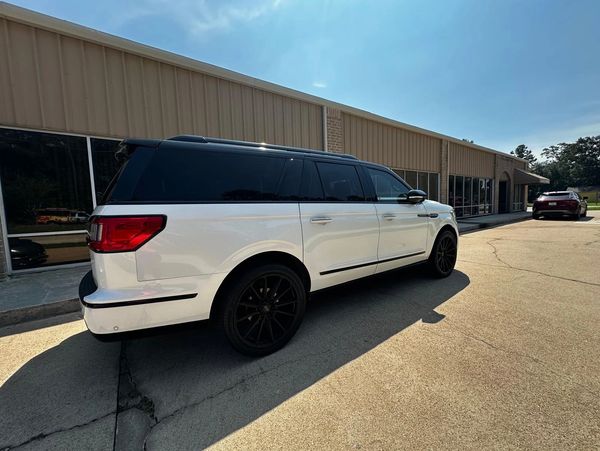 White SUV with black roof and tinted windows parked outside a commercial building.