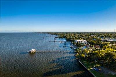 A coastal town with docks extending into calm water under a clear blue sky.