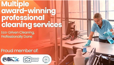 Professional cleaner wiping a desk in an office environment.