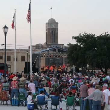 Gathered crowd at dusk in Cleburne Market Square, bustling with activity and vibrant energy.