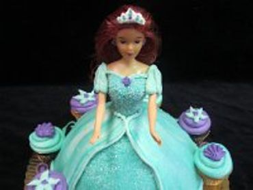 A green colored doll cake with crown on head